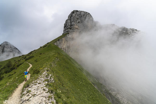 Hiker man walking on path on Saxer Lucke mountain in the morning fog, Appenzell Canton, Alpstein Range, Switzerland