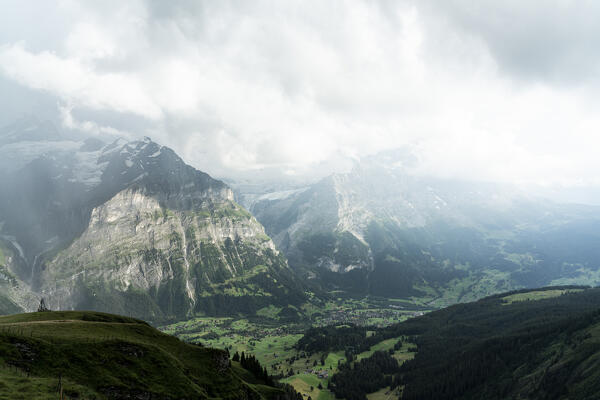 Clouds over green meadows and mountains surrounding Grindelwald view from First, Bernese Alps, Canton of Bern, Switzerland