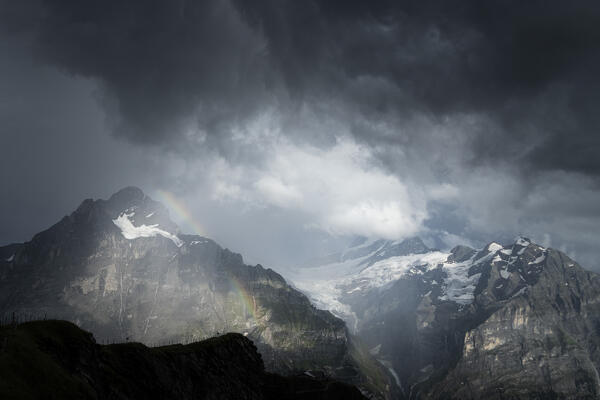 Storm clouds over Wetterhorn and Schreckhorn mountains lit by rainbow, Grindelwald, Bernese Alps, Canton of Bern, Switzerland