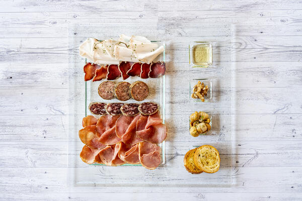 Overhead view of mixed cold cuts in glass serving plate with croutons as appetizer