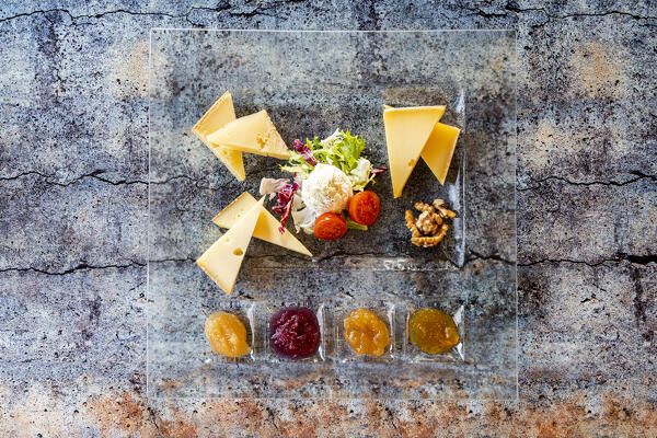 Selection of typical italian cheese served with jam in glass dish from above