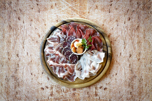 Mixed italian cold cuts appetizer in wood round chopping board from above