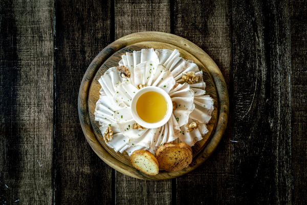 Chopping board  with lard meat, walnuts and honey appetizer on wood table background from above, Italy