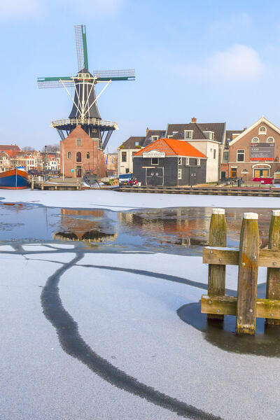 Windmill De Adriaan reflected in the canal of frozen Spaarne river, Haarlem, Amsterdam district, North Holland, The Netherlands