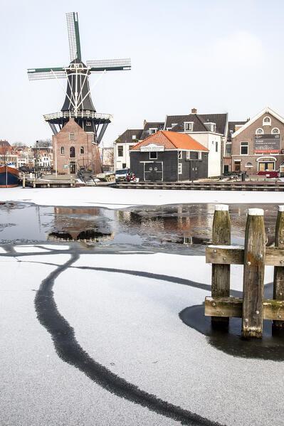 Windmill De Adriaan reflected in the canal of icy river Spaarne, Haarlem, Amsterdam district, North Holland, The Netherlands