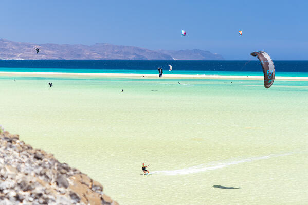 People riding the ocean waves with kiteboard at Sotavento beach, Jandia, Fuerteventura, Canary Islands, Spain