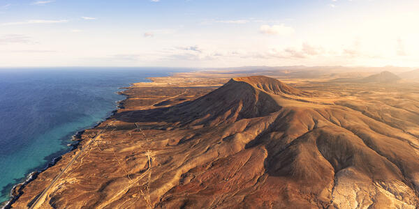 Aerial view of Montana Roja red volcanic mountain along the coastline towards Corralejo, Fuerteventura, Canary Islands, Spain