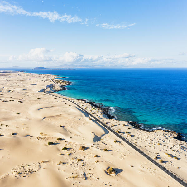 Aerial view of scenic coastal road crossing the sand dunes of Corralejo Natural Park, Fuerteventura, Canary Islands, Spain