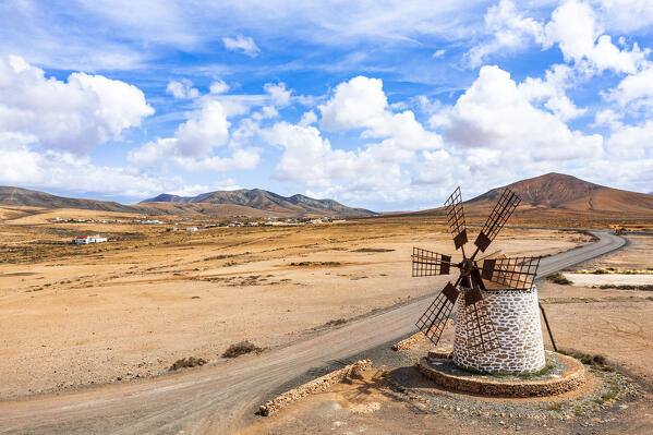 Empty desert road passing by the old stone windmill, Tefia, Fuerteventura, Canary Islands, Spain
