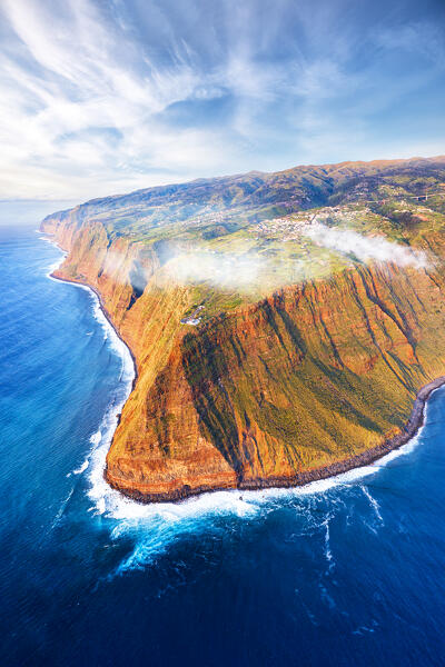 Waves crashing on the majestic Ponta do Pargo cliffs at sunset, aerial view, Calheta, Madeira island, Portugal