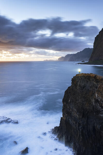 Aerial view of hiker  with headtorch standing on top of cliffs at dusk, Madeira, Portugal