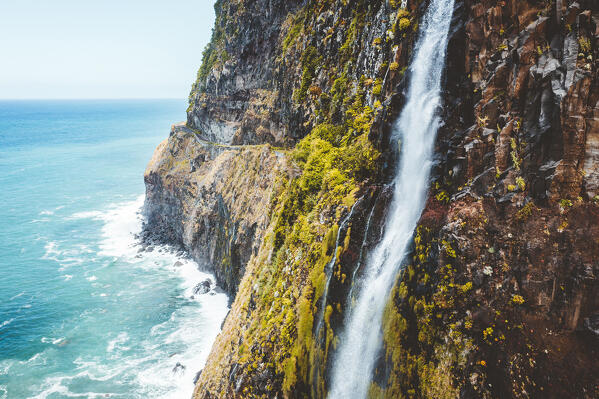 Flowing water of Bridal Veil Fall jumping from cliffs down to ocean, Seixal, Madeira island, Portugal
