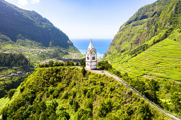 Capelinha de Nossa Senhora de Fatima clock tower on green hills surrounded by terraced fields, Sao Vicente, Madeira, Portugal