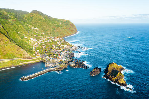Sunrise over mountains and Porto Moniz village by the ocean, aerial view,  Madeira island, Portugal