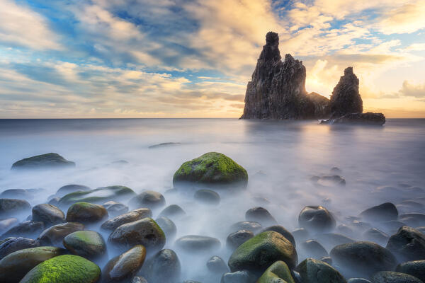 Burning sky at dawn on the ocean waves and Ilheus da Rib and Ribeira da Janela rock formations, Madeira island, Portugal