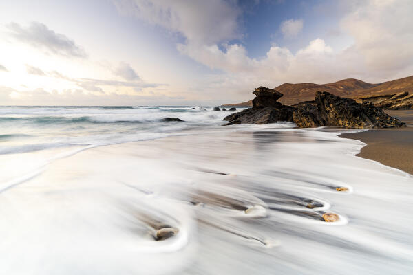 Long exposure of ocean waves breaking on sand beach Playa de la Solapa at sunset, Fuerteventura, Canary Islands, Spain