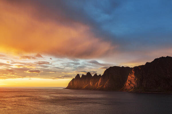 Clouds in the burning sky at midnight sun over the sharp mountain peaks Devil's Teeth, Tungeneset, Senja, Troms county, Norway