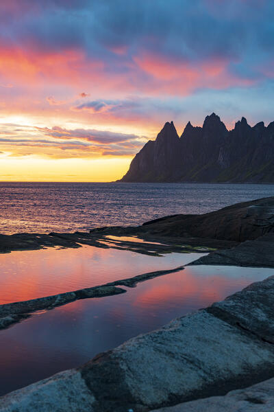 Clouds in the colorful sky of midnight sun over the sharp mountain peaks Devil's Teeth, Tungeneset, Senja, Troms county, Norway