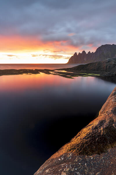 Midnight sun along the fjord and sharp mountain peaks known as Devil's Teeth, Tungeneset, Senja, Troms county, Norway