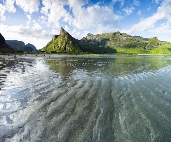 Panoramic of Hatten mountain reflected in the sea washing the empty beach, Ersfjord, Senja island, Troms county, Norway