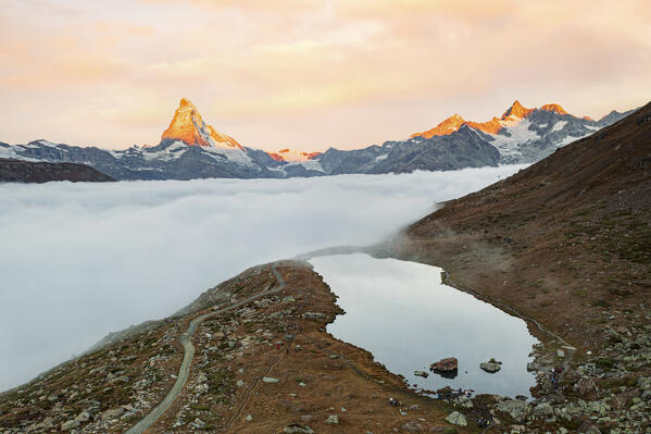 Aerial view of majestic Matterhorn peak and Stellisee lake in a sea of clouds at sunrise, Zermatt, Valais canton, Switzerland