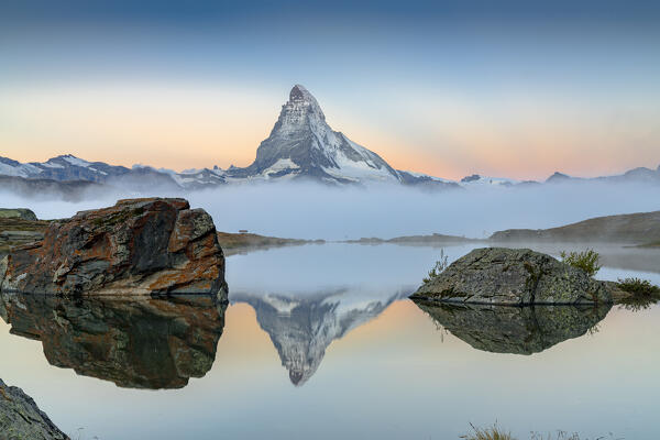 Matterhorn peak in morning mist reflected in lake Stellisee at dawn, Zermatt, Valais canton, Switzerland
