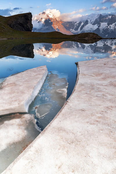 Ice blocks melting at Grauseeli lake with Jungfrau mountain on background at sunset, Murren Birg, Bern canton, Switzerland