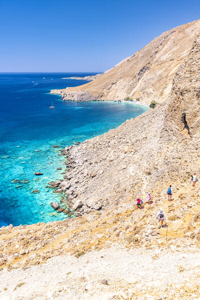 Hikers downhill on rocks towards the idyllic Glyka Nera beach in summer, Hora Sfakion, Crete island, Greece