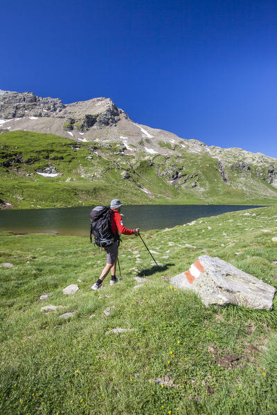 Hiker walking on the shores of the Baldiscio lake. Baldiscio lake, Campodolcino, Vallespluga, Valchiavenna, Lombardy, Italy.