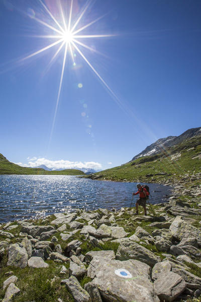 Hiker on the shores of the Baldiscio lake. Baldiscio pass, Campodolcino, Vallespluga, Valchiavenna, Lombardy, Italy.