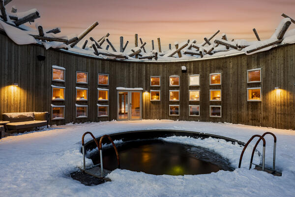 Illuminated building and sauna of Arctic Bath Spa and wellness Hotel with open-air pool for cold baths, Harads, Lapland, Sweden