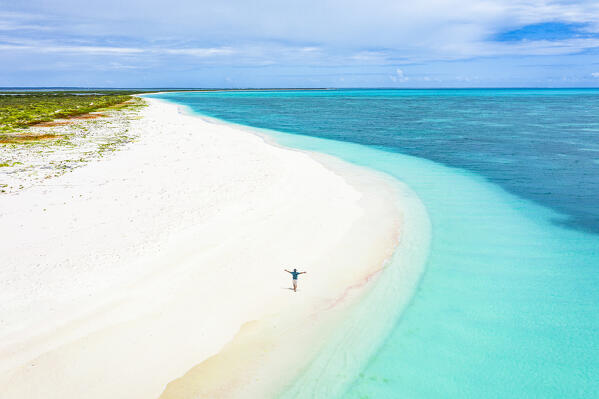 Cheerful man with arms outstretched admiring the sea standing on a white sand beach, aerial view, Antigua & Barbuda, Caribbean (MR)