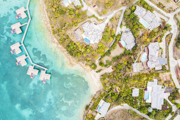 Aerial view of luxury villas with pool and overwater bungalows of tropical resort by the turquoise sea, Antigua, Caribbean