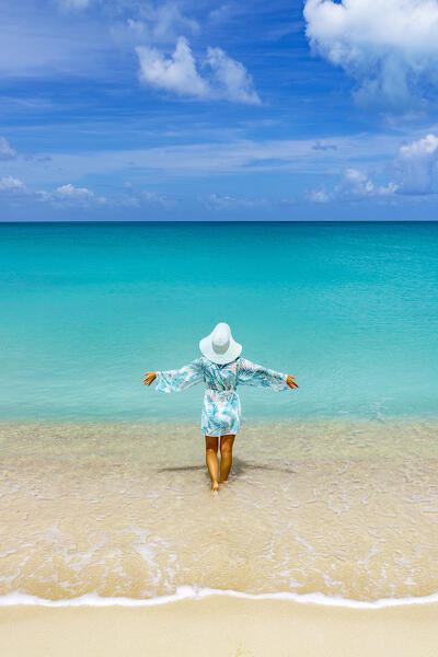 Beautiful woman in turquoise dress rejoices in the crystal water of Caribbean Sea, overhead view, Antigua & Barbuda, West Indies