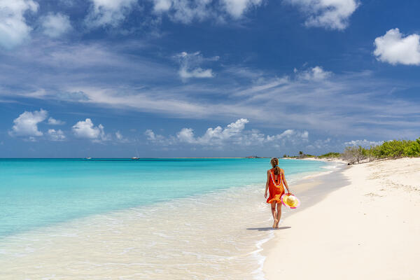 Beautiful woman in orange dress walking on a idyllic beach, Barbuda, Antigua & Barbuda, Caribbean, West Indies (MR)