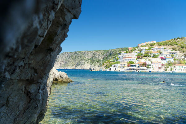 Crystal clear sea surrounding the colorful houses of Assos village in summer, Kefalonia, Ionian Islands, Greece