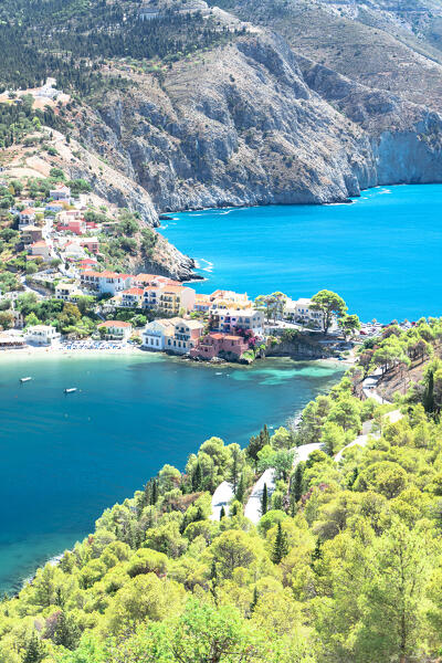 Winding road among green trees towards the colorful village of Assos by the sea, Kefalonia, Ionian Islands, Greece