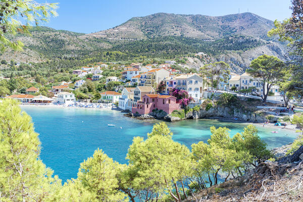 Trees framing the picturesque village and beach of Assos overlooking the clear blue sea, Kefalonia, Ionian Islands, Greece