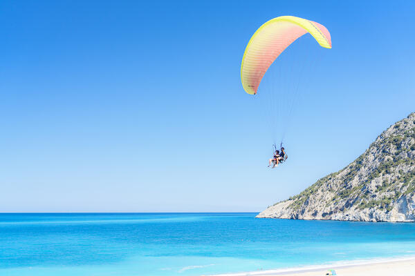 Two people on paraglide enjoying flying over the turquoise clear sea at Myrtos beach, Kefalonia, Ionian Islands, Greece