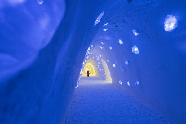 Tourist walking in a illuminated tunnel built with ice, Lainio Snow Village, Kittila, Lapland, Finland