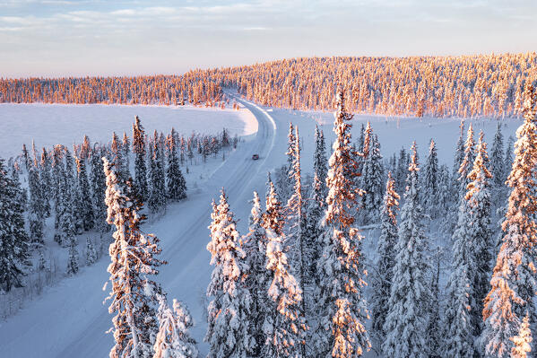 Aerial view of car driving on an icy road in the snowy forest, Kangos, Norrbotten County, Lapland, Sweden
