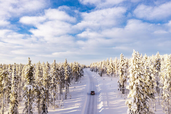 Aerial view of car driving on an icy road in the snowy forest, Kangos, Norrbotten County, Lapland, Sweden