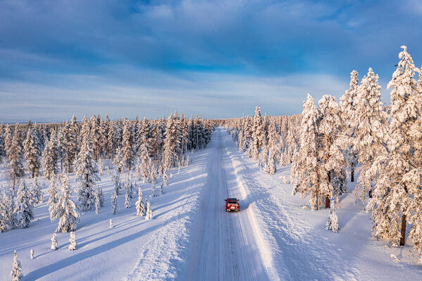 High angle view of car driving on an icy road among trees covered with snow, Kangos, Lapland, Sweden