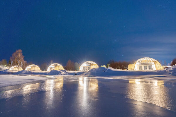 Starry sky at dusk over the illuminated glass igloo on the snowy shores of the frozen river Kalix, Ice and Light village,
Kalix, Norrbotten county, Lapland, Sweden