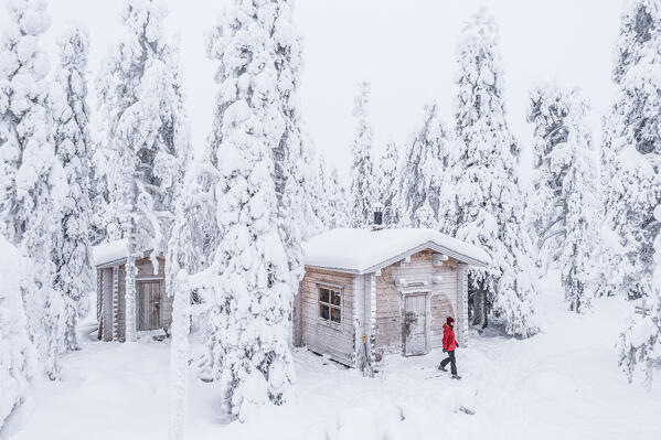 Aerial view of woman walking out of a snowy hut, Iso Syote, Northern Ostrobothnia, Lapland, Finland