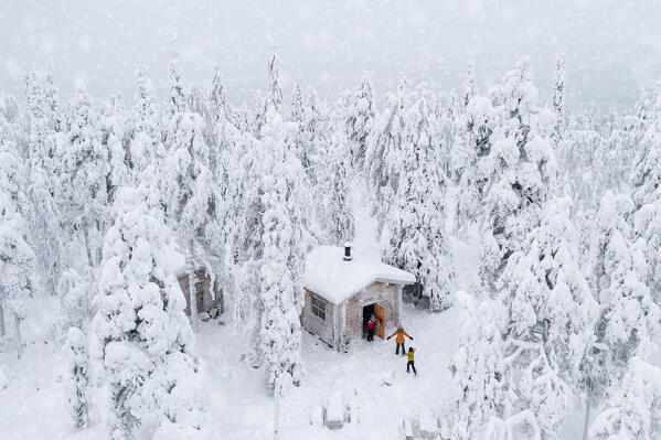 Aerial view of happy family enjoying staying in a snowy hut into the frozen forest, Iso Syote, Northern Ostrobothnia, Lapland, Finland (MR)
