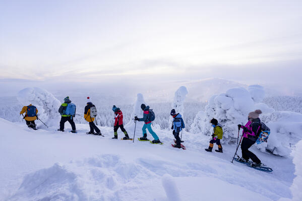Group of tourists admiring the ice sculptures snowshoeing on a winter trail, Oulanka National Park, Ruka Kuusamo, Lapland, Finland