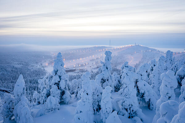 Foggy sky at dusk over the snowy forest and ski slopes of Ruka tourist resort, Kuusamo, Northern Ostrobothnia, Lapland, Finland