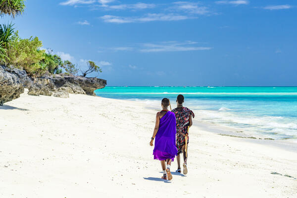 Young Masaai couple with colorful tradizional clothing walking on a beach in summer, Zanzibar, Tanzania