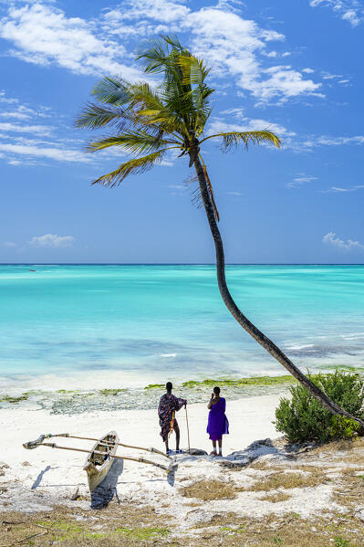 Couple of Maasai with dhow admiring the crystal sea standing on a palm fringed beach, Zanzibar, Tanzania (MR)